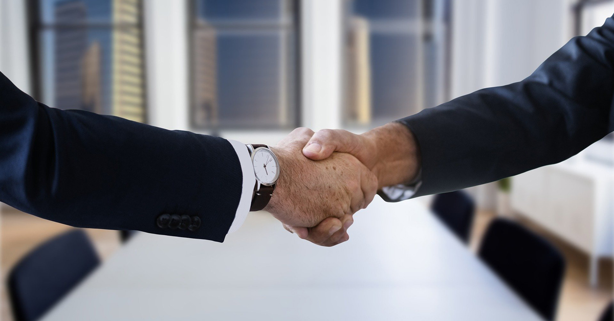 a business lawyer and corporate attorney shaking hands in a conference room after making a deal