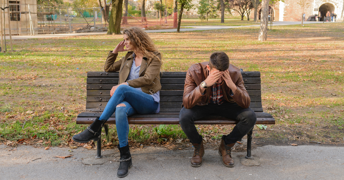 a couple sitting on a bench upset with each other after discussing divorce