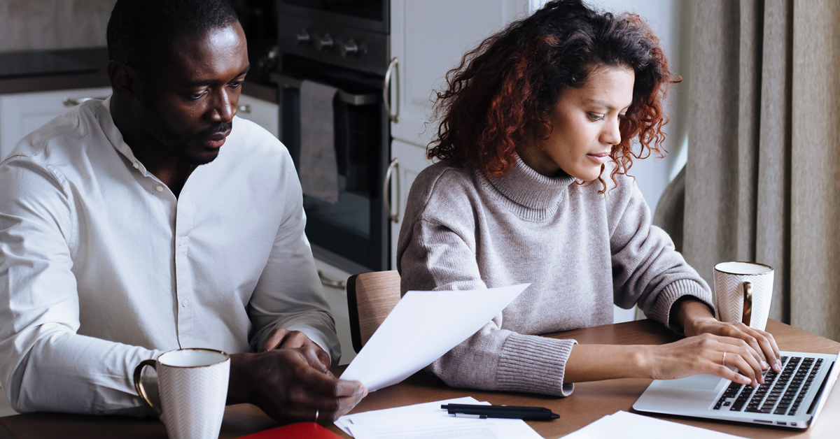 couple looking at estate planning documents at home in front of laptop